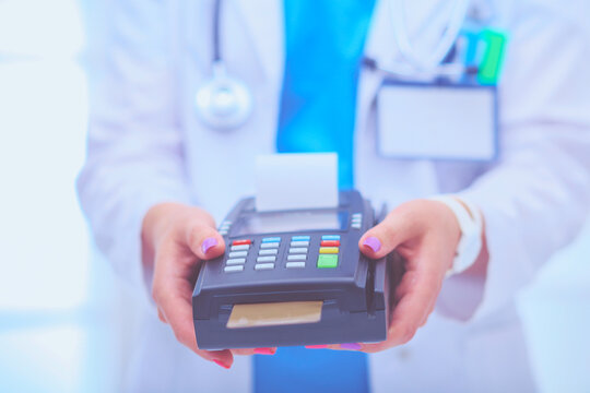 Doctor is holding payment terminal in hands. Paying for health care. Doctor