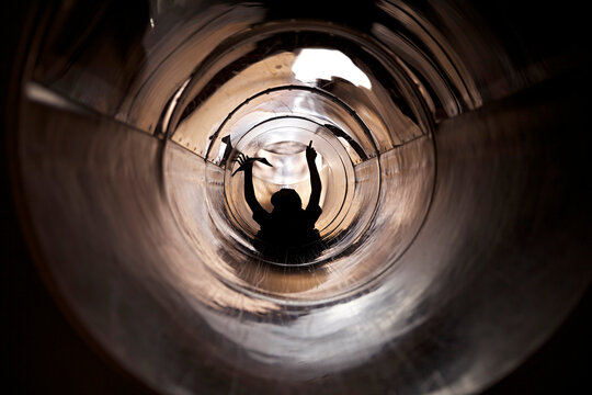 Young child's silhouette inside tubular slide