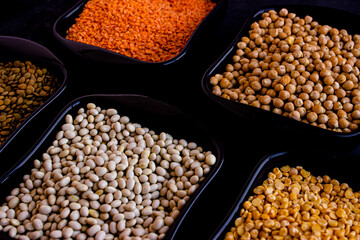 Orange lentils, white beans, peas in dark plates