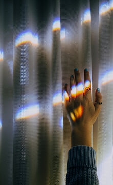 Female hand reaching up toward a prism of light