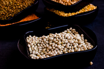 Orange lentils, white beans, peas in dark plates