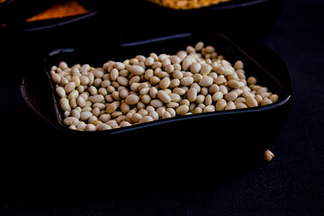 Orange lentils, white beans, peas in dark plates