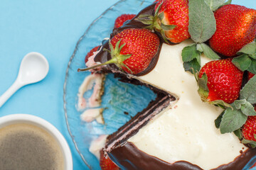 Homemade chocolate cake decorated with fresh strawberries and cup of coffee