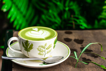 Hot green tea in a white cup on a wooden table