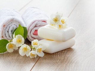 Fototapeta na wymiar White towels and soap for bathroom procedures and flowers of jasmine