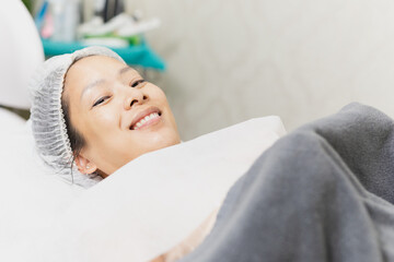 Obraz na płótnie Canvas Smiling of beautiful woman with clean healthy skin relaxing lying in spa salon.