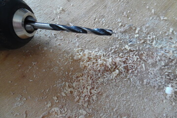 Nahaufnahme des Bohrkopfes eines Akkuschraubers auf Holz mit Sägespänen . Holzspäne verursacht...