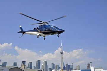 blue and white helicopter in the air, Toronto city center skyline in the background  © skyf