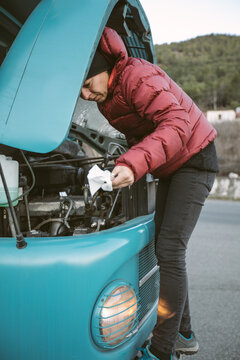 woman with red jacket checking the oil level from an old turqouise truck