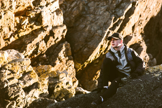 Teenage boy sitting on rocks.