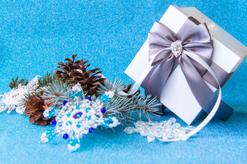 Christmas gift with a gray bow. Gift box, branch, spruce and fir cone.