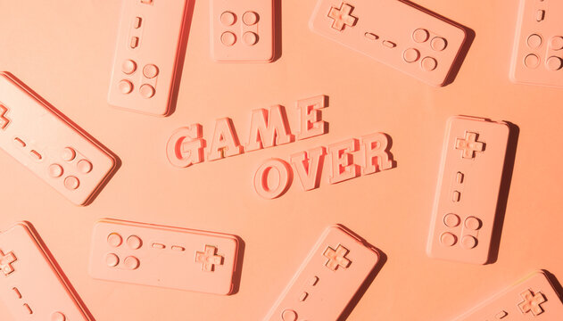 Gaming console josticks arranged with word ""Game over""