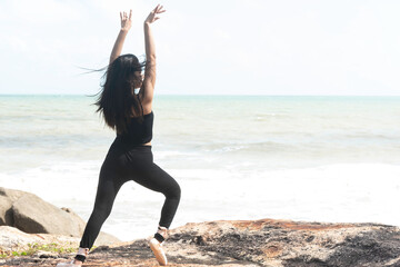 Beautiful young asian student woman ballerina practice ballet dance,stone and sea background ,Beauty of classic ballet.
