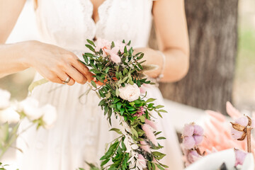 Workshop florist, making bouquets and flower arrangements. Girl makes wreath at head. Process of weaving a wreath with herbs and flowers. Lesson of florists close-up. Copy space