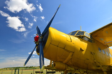 Close-up view of an old yellow plane. Isolated yellow bi plane on grassy meadow under blue sky with...