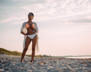 Fototapeta na wymiar beautiful woman in white bikini on beach at sunset