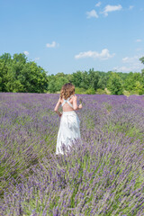 A brunette curly hair girl running in the purple field of lavender in Provence 