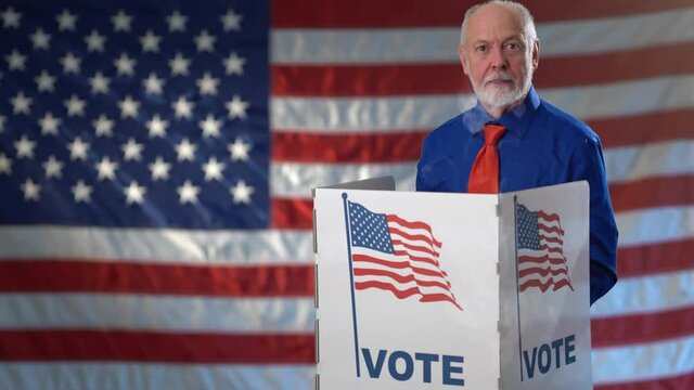 Conceptual funny portrait on US flag background of angry frustrated man in voting booth at ballot box, careful decision for president, in US election.
