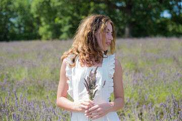 Fototapeta premium Brunette curly hair girl standing in the lavender field in France