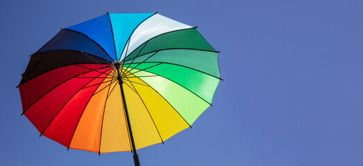 Umbrella rainbow colors on blue sky background, inside shot © Rawf8