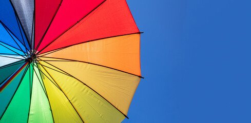 Umbrella rainbow colors on blue sky background, inside shot