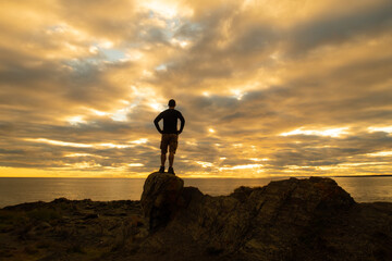 Back view of a man standing on a rock and facing the St Lawrence river estuary in the Bic national...