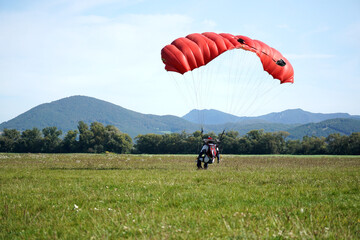 Parachutist jamped from an airplane uses a parachute to land.
