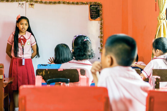 Young Female Student Recites in front of Class in School