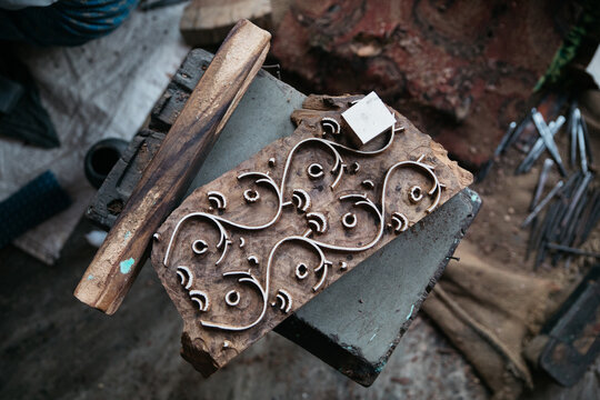 man cuts decorative pattern by hand in wood block for printing Jaipur india