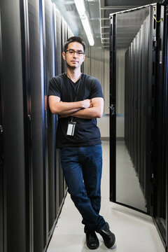 Portrait of server room technician leaning against a bank of ser