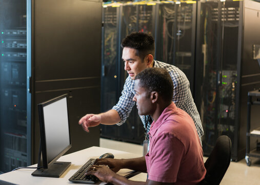 Two technicians talk while looking at computer monitor in server
