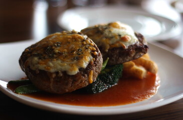 Close up of a plate of delicious beef hamburgers served with french fries and vegetable and garlic sauce