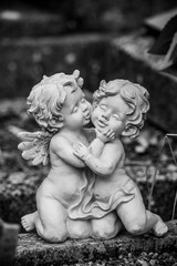 Closeup of stoned angels kissing on tomb in a cemetery