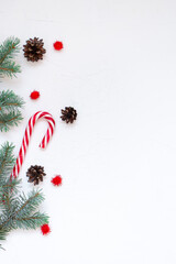 Fototapeta na wymiar Christmas composition. Fir branches, cones, New Year's lollipop, red decorations on a white background. Christmas, winter, new year concept. Flat lay, top view, copy space 