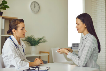 Young patient telling doctor about her health problems, describing symptoms and asking for advice