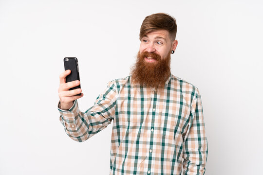 Redhead man with long beard over isolated white background making a selfie