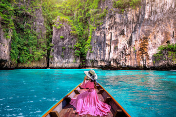 Beautiful girl sitting on the boat and looking to mountains in Phi phi island, Thailand. - obrazy, fototapety, plakaty
