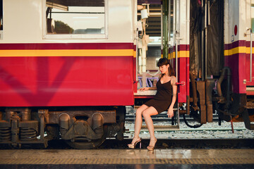 Fashion model asian woman with makeup posing at platform train station with sunlight and shadow reflection.