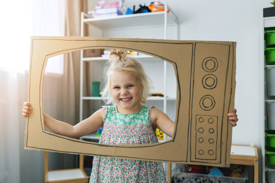 cheerful child playing with cardboard tv at home. future dream profession concept