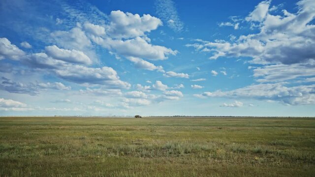 The tractor is on the horizon. Field seasonal work. Agricultural transport in the steppe. Clear blue sky. Sunny day over the wide steppe.