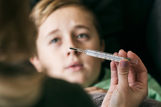 Sick: Mother Checking Temperature Of Young Boy