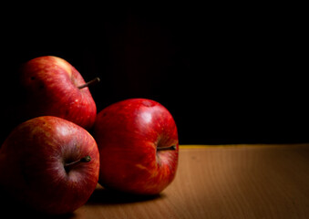 Fototapeta na wymiar Bunch of apples stacked together on a wooden table with a dark background