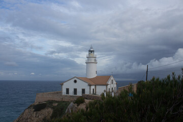 Fototapeta na wymiar Lighthouse at the top of Capdepera, Majorca, Spain. Romantic view of mountain, sea and clouds.