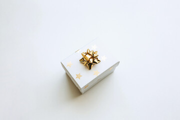 Gift box with a gold bow on a white background in a minimal style. Festive concept.