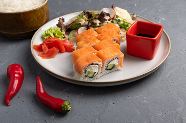 Japanese sushi food. Philadelphia rolls and mixed vegetable salad on a light plate close-up. gray background. top view