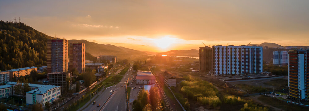 Evening panorama of the city outskirts. Hills and mountains at sunset, urban landscape and new buildings © Vladimir Razgulyaev