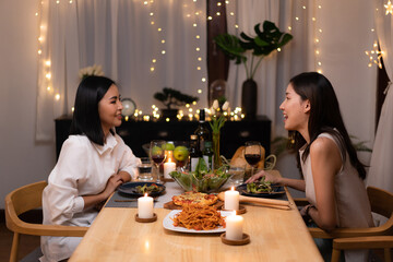 Asian young lesbian couple have a romantic, candlelit dinner in her home.