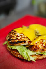 Chicken burger with melted cheddar cheese cooked on grill in American diner cafe.Hamburger sandwich preparation in fast food restaurant kitchen