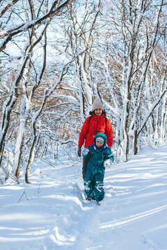 Mother and son walking in the winter forest