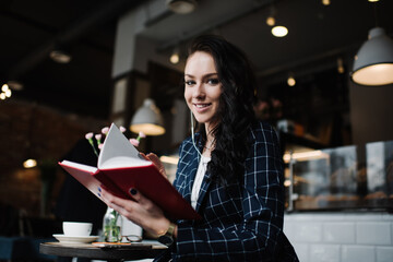 Positive woman in cafe looking through book